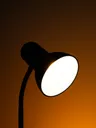 A desk lamp glowing against an amber wall